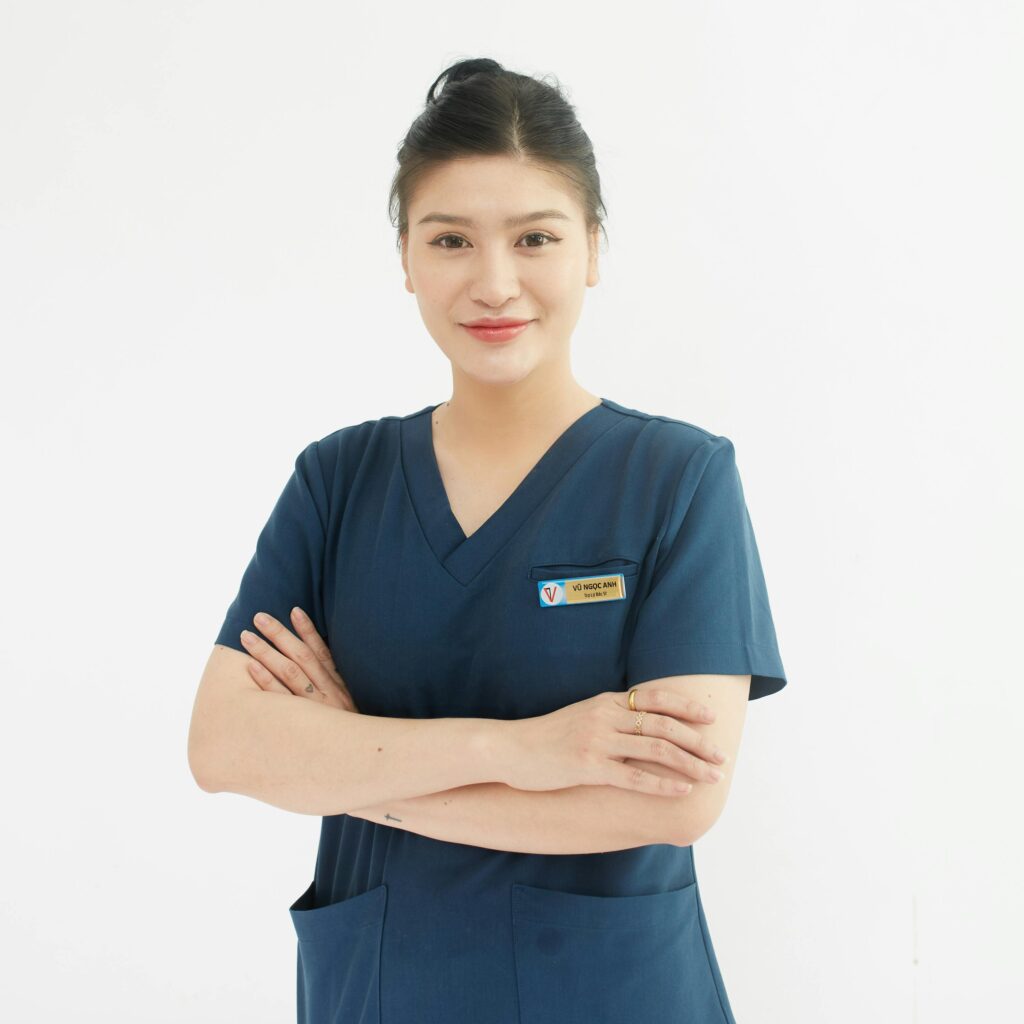 Offerings Professional portrait of a smiling female nurse with folded arms in a medical uniform.