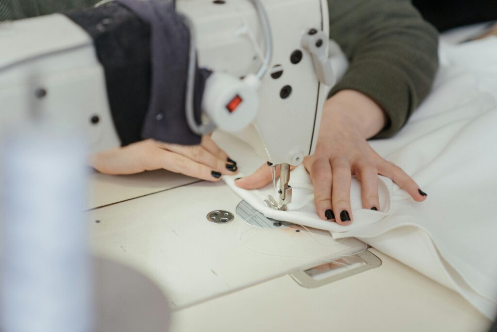 Contact Close-up of hands sewing fabric on a professional sewing machine in a workshop.