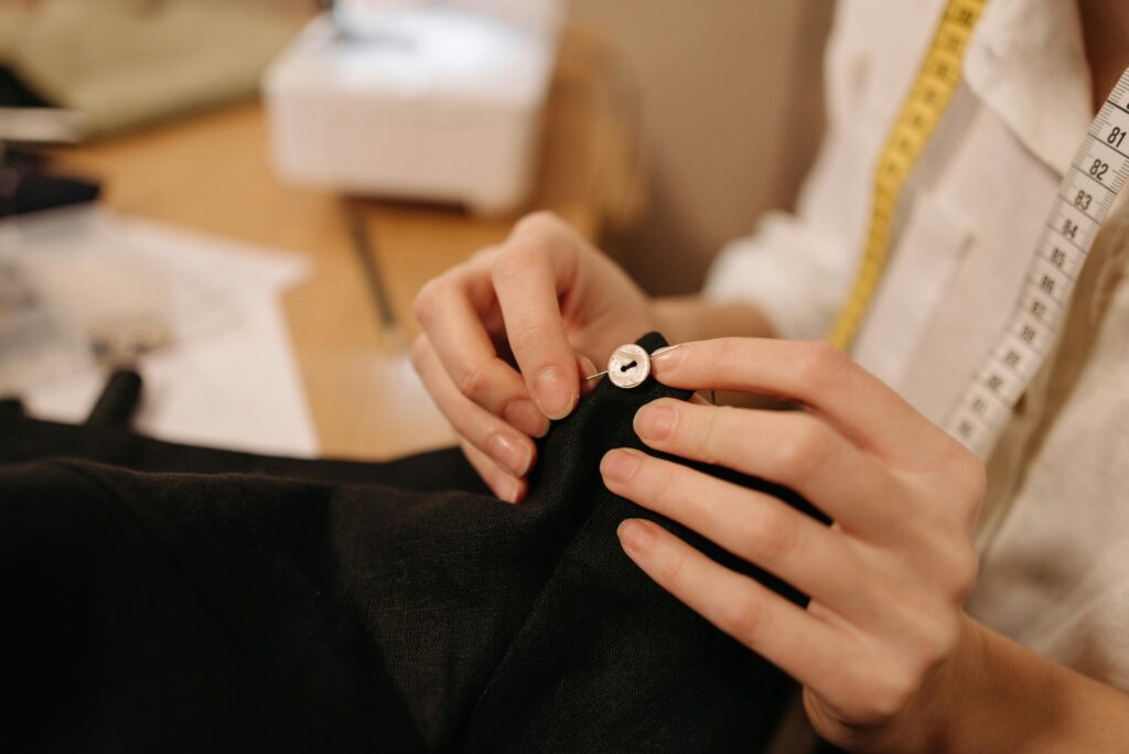 About Close-up of a tailor sewing a button with a needle and thread.