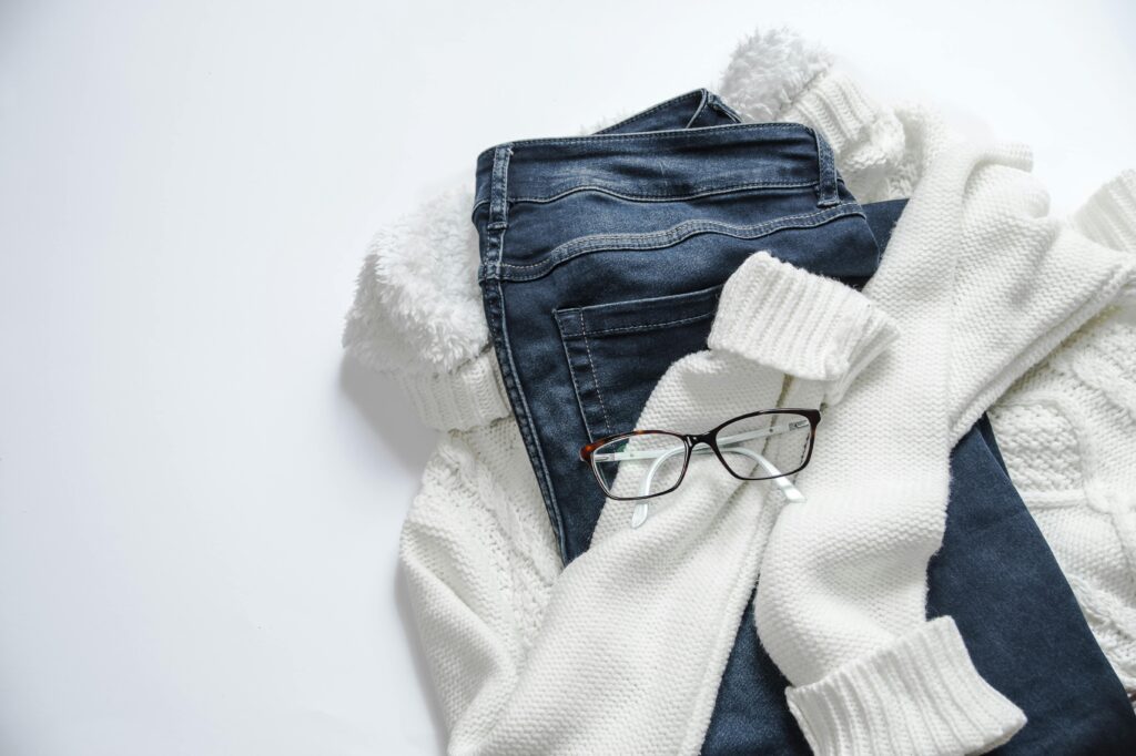 pexels photo 934070 934070 Stylish flat lay featuring denim jeans, white sweater, and eyeglasses on a bright background.